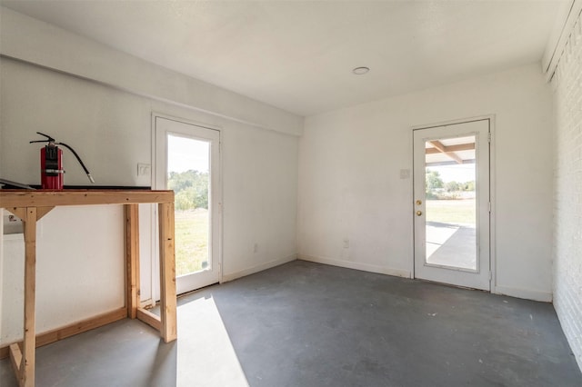 doorway to outside featuring concrete floors and baseboards