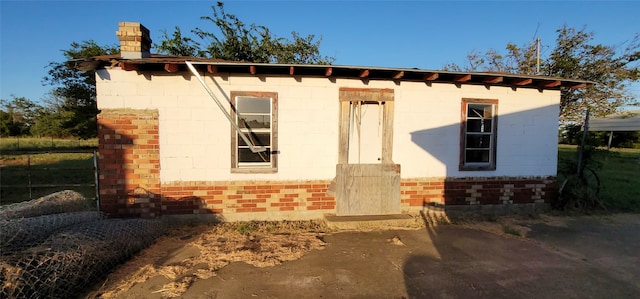 view of front of home with a chimney and brick siding