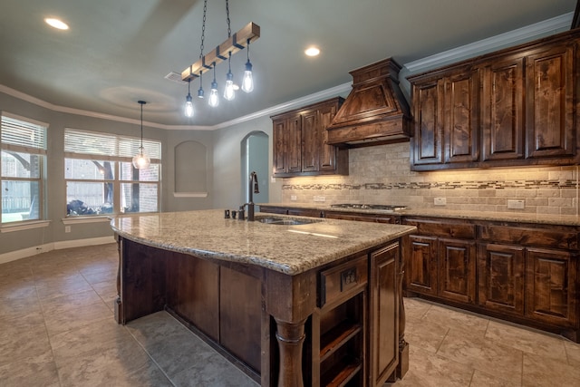 kitchen featuring custom range hood, hanging light fixtures, a kitchen island with sink, light stone countertops, and light tile patterned floors