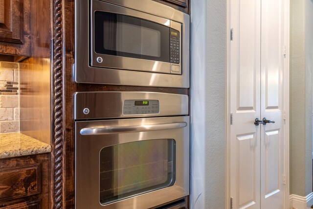 kitchen with appliances with stainless steel finishes, light stone counters, backsplash, and dark brown cabinets