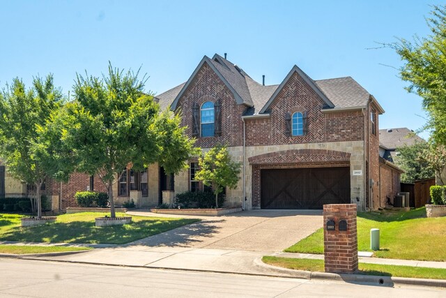 view of front of house with a garage, central AC, and a front yard