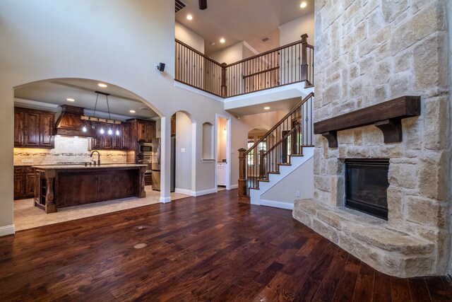 unfurnished living room featuring hardwood / wood-style flooring, a fireplace, sink, and a high ceiling