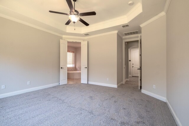 unfurnished bedroom with ceiling fan, light carpet, a tray ceiling, connected bathroom, and crown molding