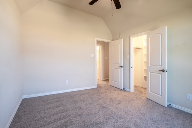 unfurnished bedroom featuring a walk in closet, a closet, light carpet, ceiling fan, and lofted ceiling