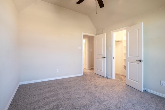 unfurnished bedroom featuring a closet, lofted ceiling, a spacious closet, ceiling fan, and light colored carpet