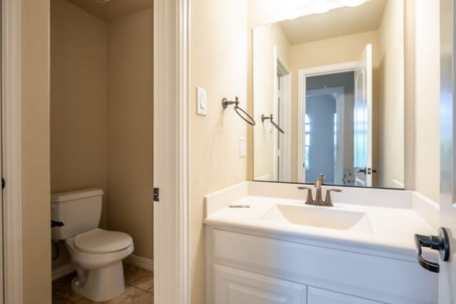 bathroom with toilet, vanity, and tile patterned flooring