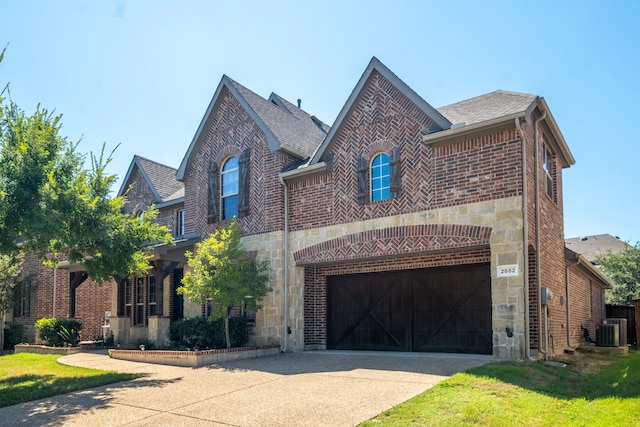 view of front of house featuring cooling unit, a garage, and a front yard