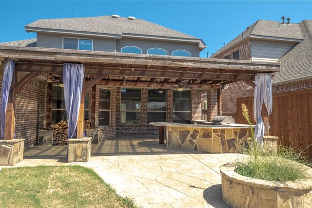 rear view of house with ceiling fan, an outdoor bar, a patio, and an outdoor kitchen