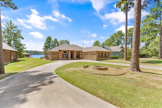 single story home featuring a fire pit, cooling unit, a garage, a water view, and a front lawn