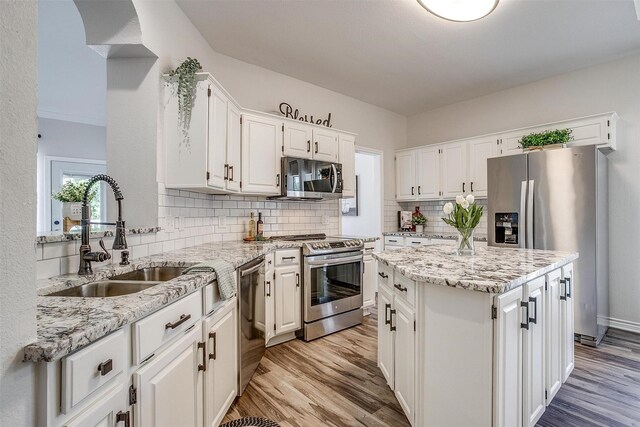 kitchen featuring light stone countertops, sink, stainless steel appliances, light hardwood / wood-style flooring, and white cabinets