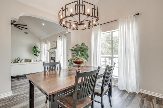 dining room with hardwood / wood-style flooring, ceiling fan with notable chandelier, lofted ceiling, and ornamental molding