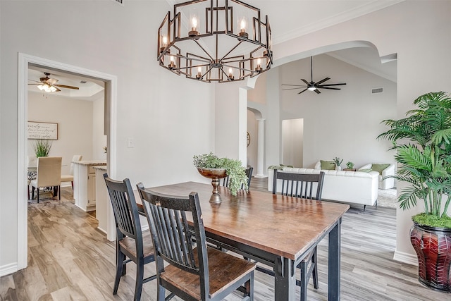 dining space featuring vaulted ceiling, crown molding, light hardwood / wood-style floors, and ceiling fan with notable chandelier