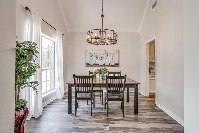 dining area featuring hardwood / wood-style floors, plenty of natural light, crown molding, and a chandelier