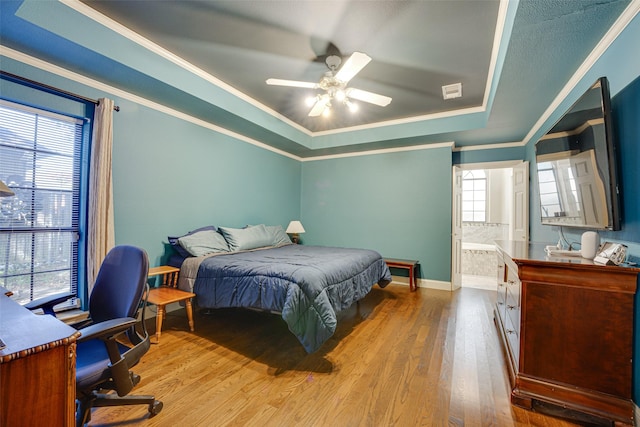 bedroom featuring multiple windows, hardwood / wood-style floors, ensuite bath, and ceiling fan