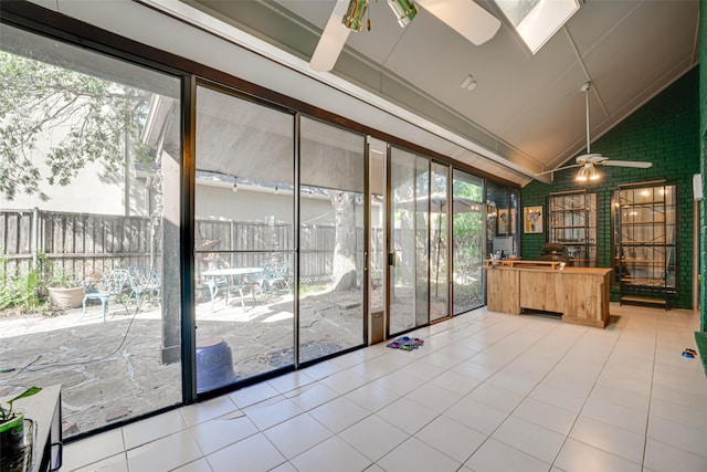 doorway to outside with lofted ceiling with skylight, ceiling fan, and light tile patterned flooring