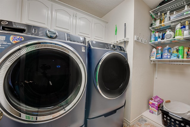 clothes washing area with washer and dryer, cabinets, and a textured ceiling