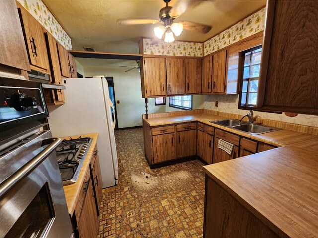 kitchen featuring sink, ceiling fan, dark tile patterned floors, and stainless steel gas stovetop