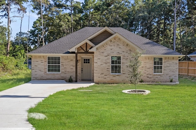 ranch-style house featuring brick siding, fence, a front yard, and roof with shingles