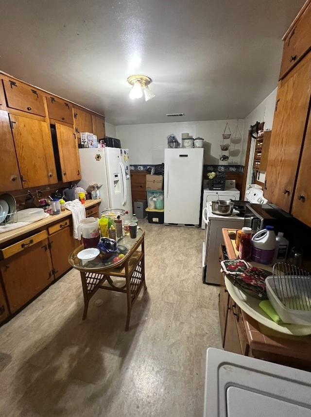 kitchen featuring white refrigerator, white refrigerator with ice dispenser, and stove