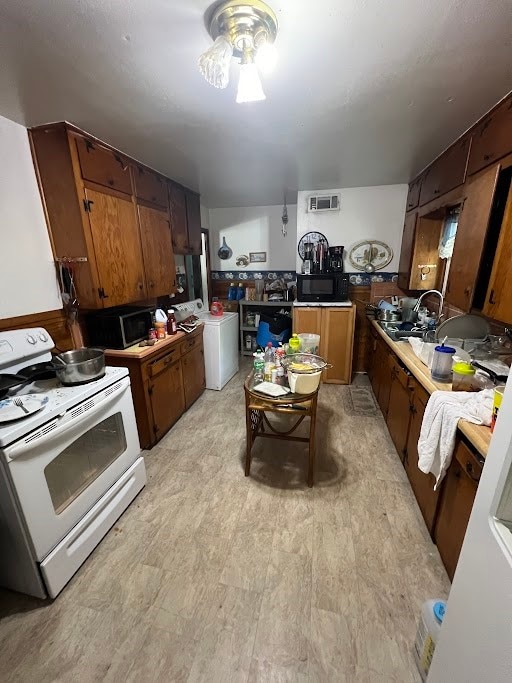 kitchen featuring white stove, ceiling fan, washer / dryer, and sink