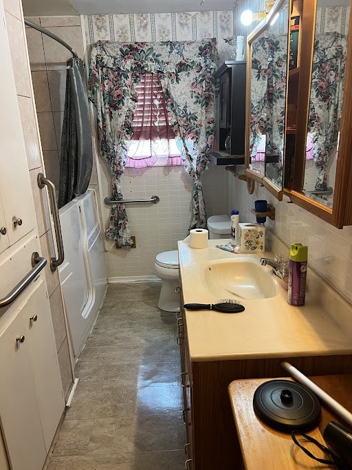 bathroom featuring tile walls, decorative backsplash, vanity, and toilet