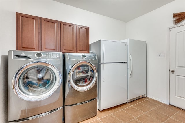 washroom featuring cabinets, washing machine and dryer, and light tile patterned floors