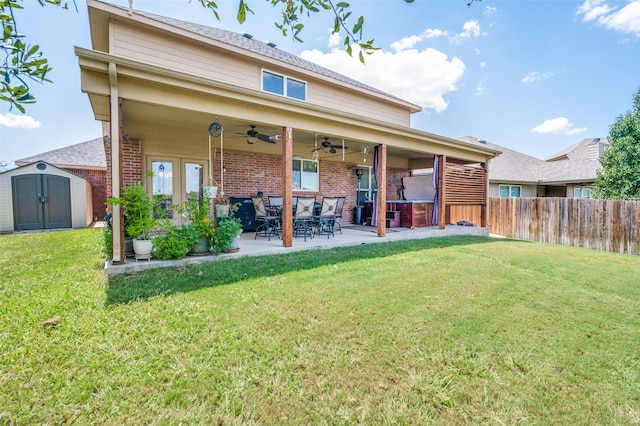 rear view of property featuring a shed, a patio area, and a lawn