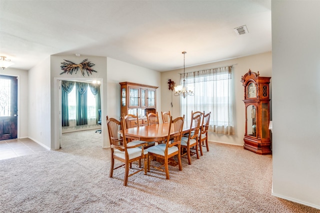 dining area with an inviting chandelier, plenty of natural light, and light carpet