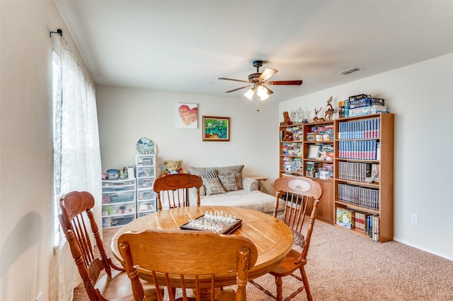 carpeted dining room with ceiling fan