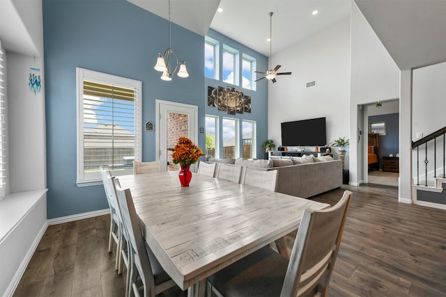 dining area featuring a wealth of natural light, ceiling fan with notable chandelier, dark wood-type flooring, and a towering ceiling