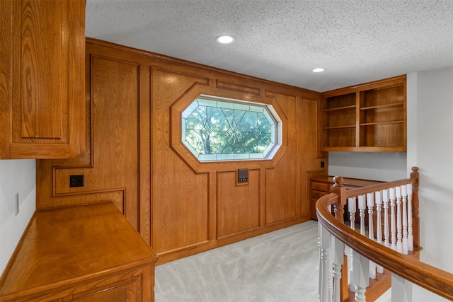 interior space with light carpet, a textured ceiling, and wooden walls