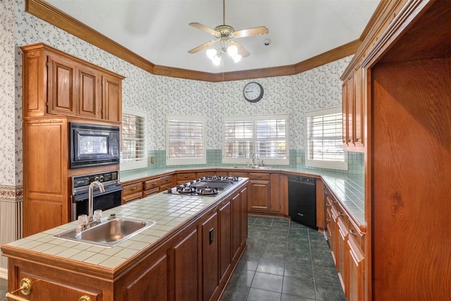 kitchen with sink, ornamental molding, black appliances, tile countertops, and a center island