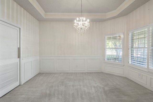 spare room featuring light carpet, plenty of natural light, and a chandelier