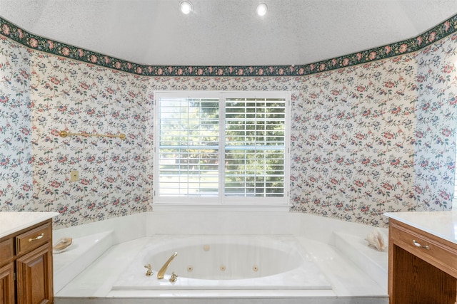 bathroom with a tub to relax in, vanity, and a textured ceiling