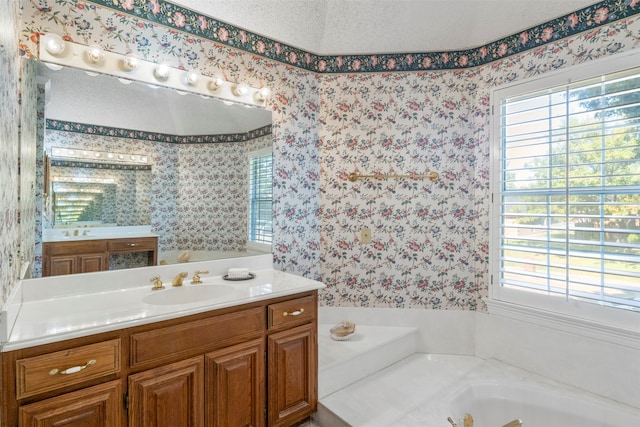 bathroom with a textured ceiling, vanity, and a healthy amount of sunlight