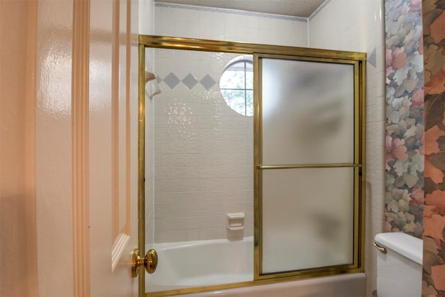 bathroom with combined bath / shower with glass door, toilet, and a textured ceiling