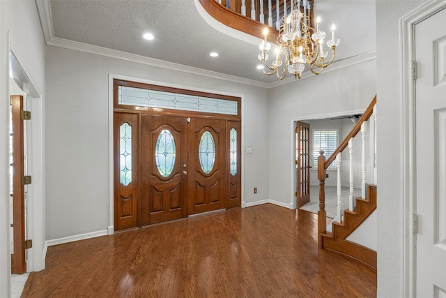 foyer entrance with ornamental molding, hardwood / wood-style floors, an inviting chandelier, and a textured ceiling