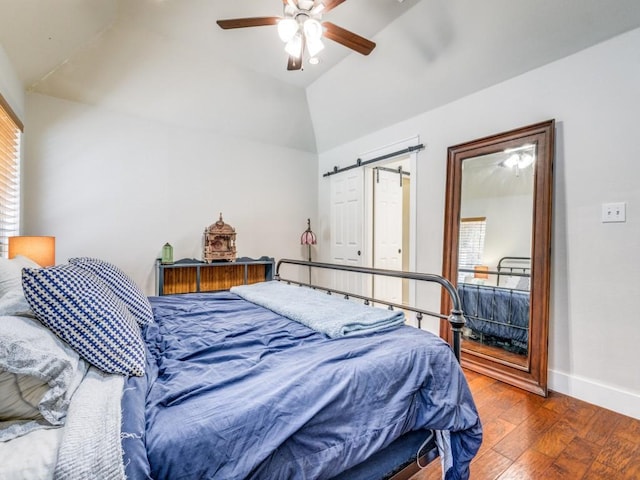 bedroom featuring hardwood / wood-style flooring, a barn door, lofted ceiling, and ceiling fan