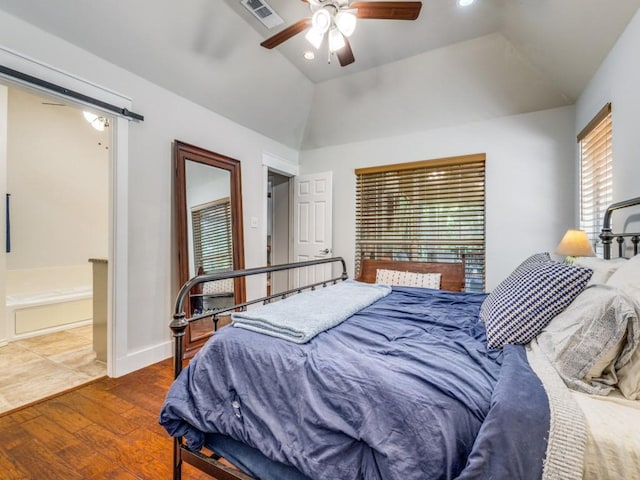 bedroom featuring hardwood / wood-style flooring, ceiling fan, a barn door, and vaulted ceiling