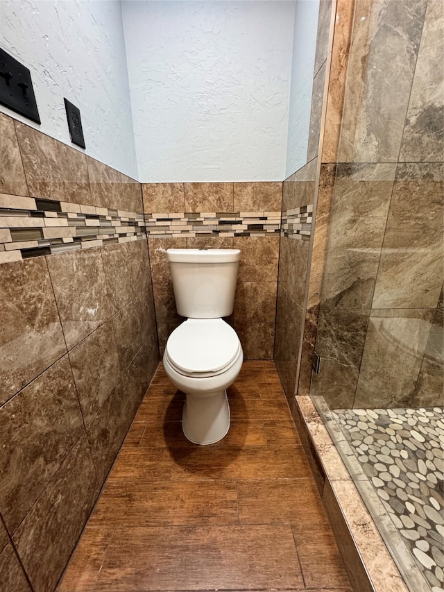 bathroom featuring tile walls, tile patterned flooring, a tile shower, and toilet