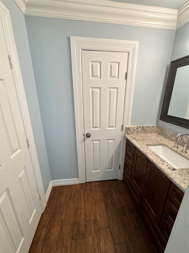 bathroom with crown molding, vanity, and hardwood / wood-style floors