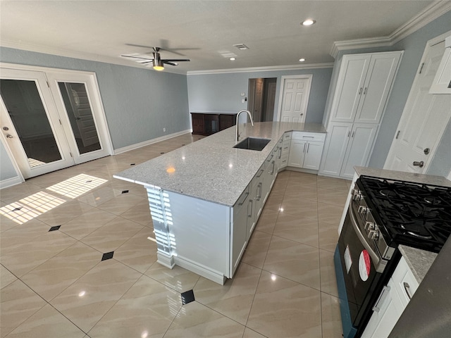 kitchen featuring ornamental molding, sink, light stone counters, stainless steel gas range, and ceiling fan