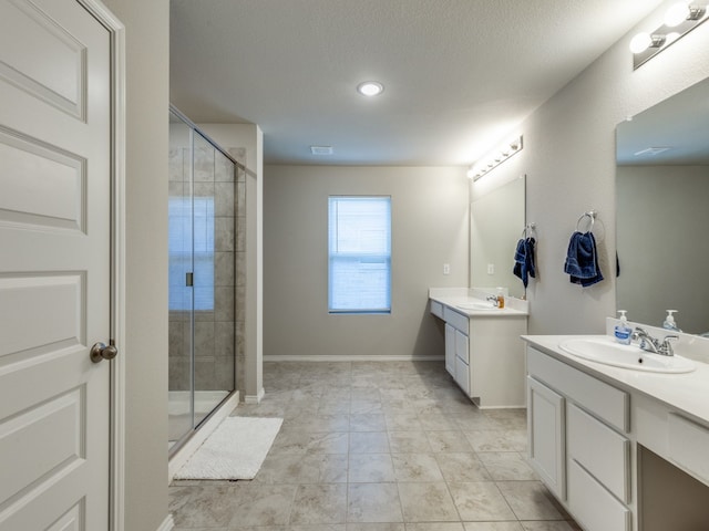 bathroom with a textured ceiling, double vanity, a shower with door, and tile patterned floors