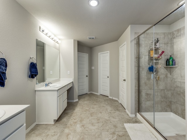 bathroom with tile patterned flooring, a textured ceiling, a shower with door, and dual vanity