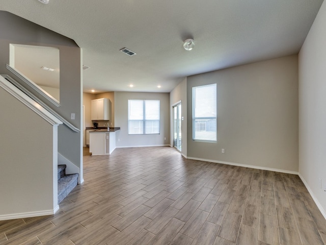 unfurnished living room featuring light wood-type flooring and sink