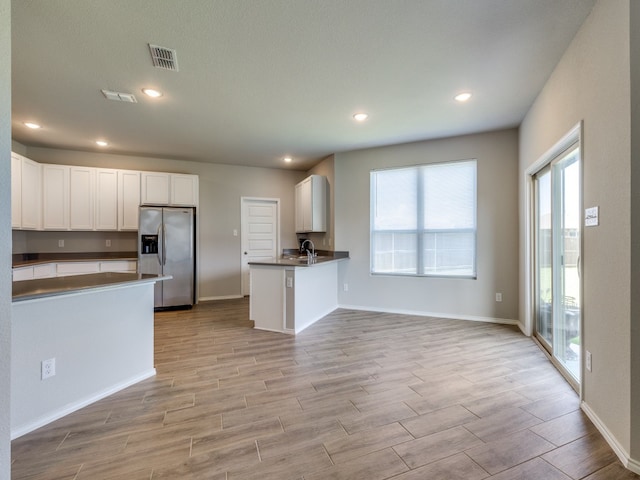 kitchen with a wealth of natural light, kitchen peninsula, and stainless steel fridge