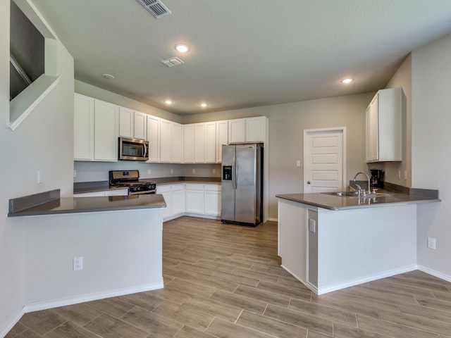 kitchen featuring white cabinetry, sink, stainless steel appliances, and kitchen peninsula