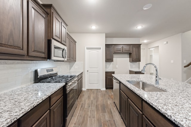 kitchen with dark brown cabinets, stainless steel appliances, light hardwood / wood-style floors, and sink