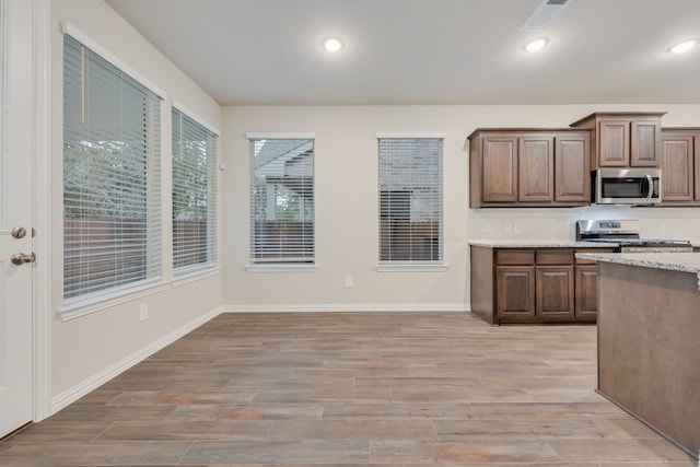 kitchen featuring light stone countertops, stainless steel appliances, and light wood-type flooring