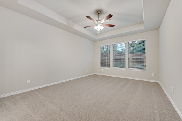 carpeted empty room featuring a tray ceiling and ceiling fan